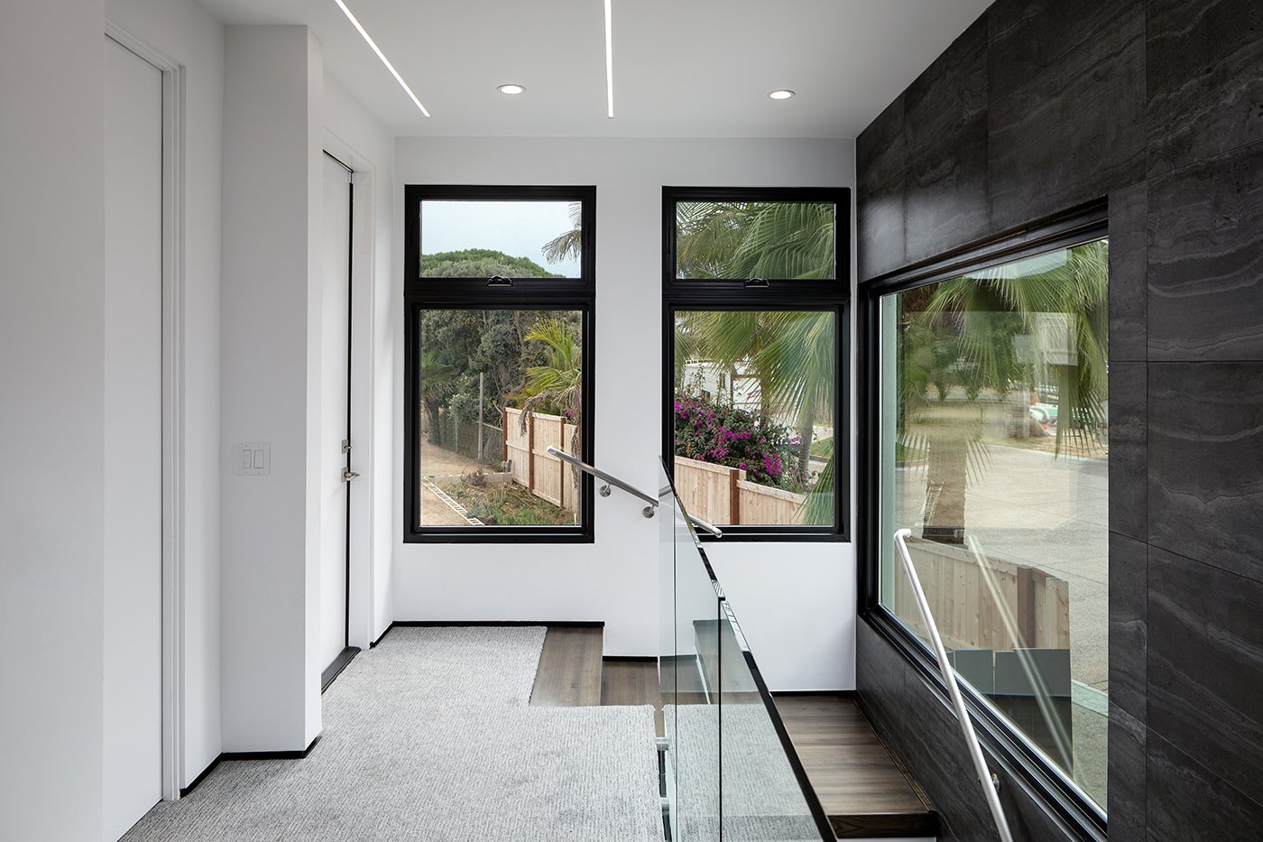 Picture and awning windows are combined in two different openings at the top of a staircase where they serve to bring in lots of natural light.