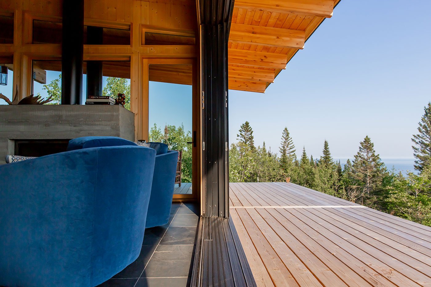 Image of a 6-panel MultiGlide Door fully pocketed in the wall, creating an open space between the living room and deck overlooking the outdoors of Grand Marais, Minnesota.