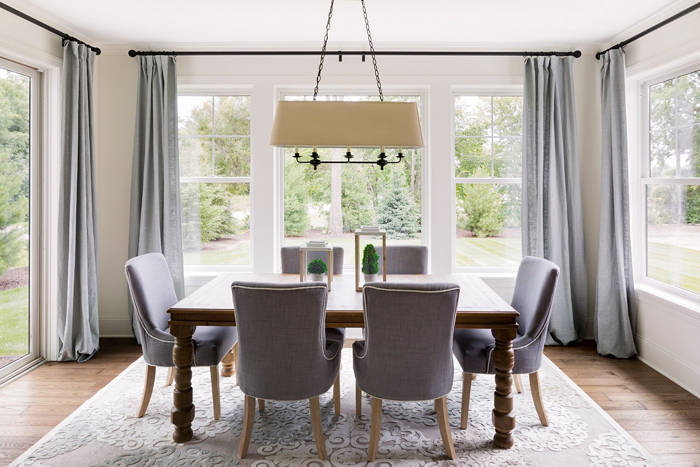 A dining room with a large window combination featuring a picture window flanked by single-hung windows on one wall and single-hung windows and a door on the other two walls.
