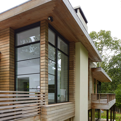 close up of corner of modern home with wood siding and black framed Andersen windows