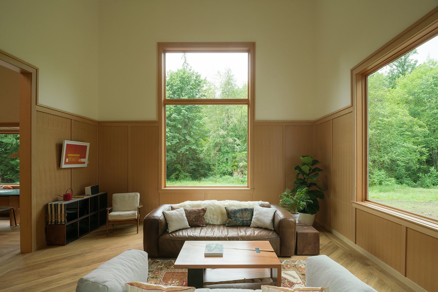 A living room with Andersen® E-Series Picture Windows that integrate with the Douglas fir wood paneling.