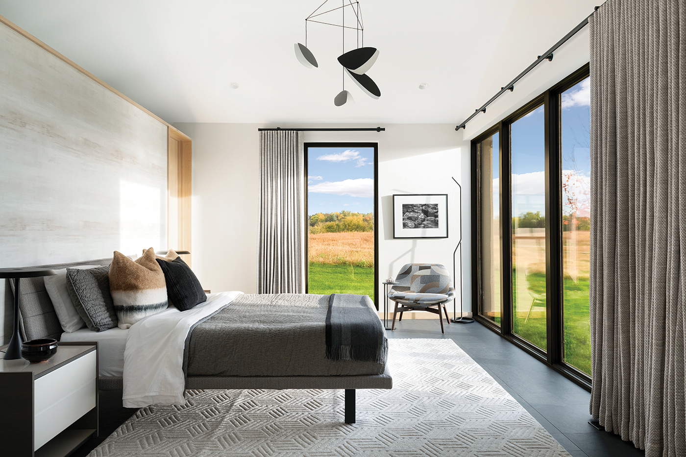 A bedroom with a whole wall of Andersen E-Series Picture Windows that overlook a prairie